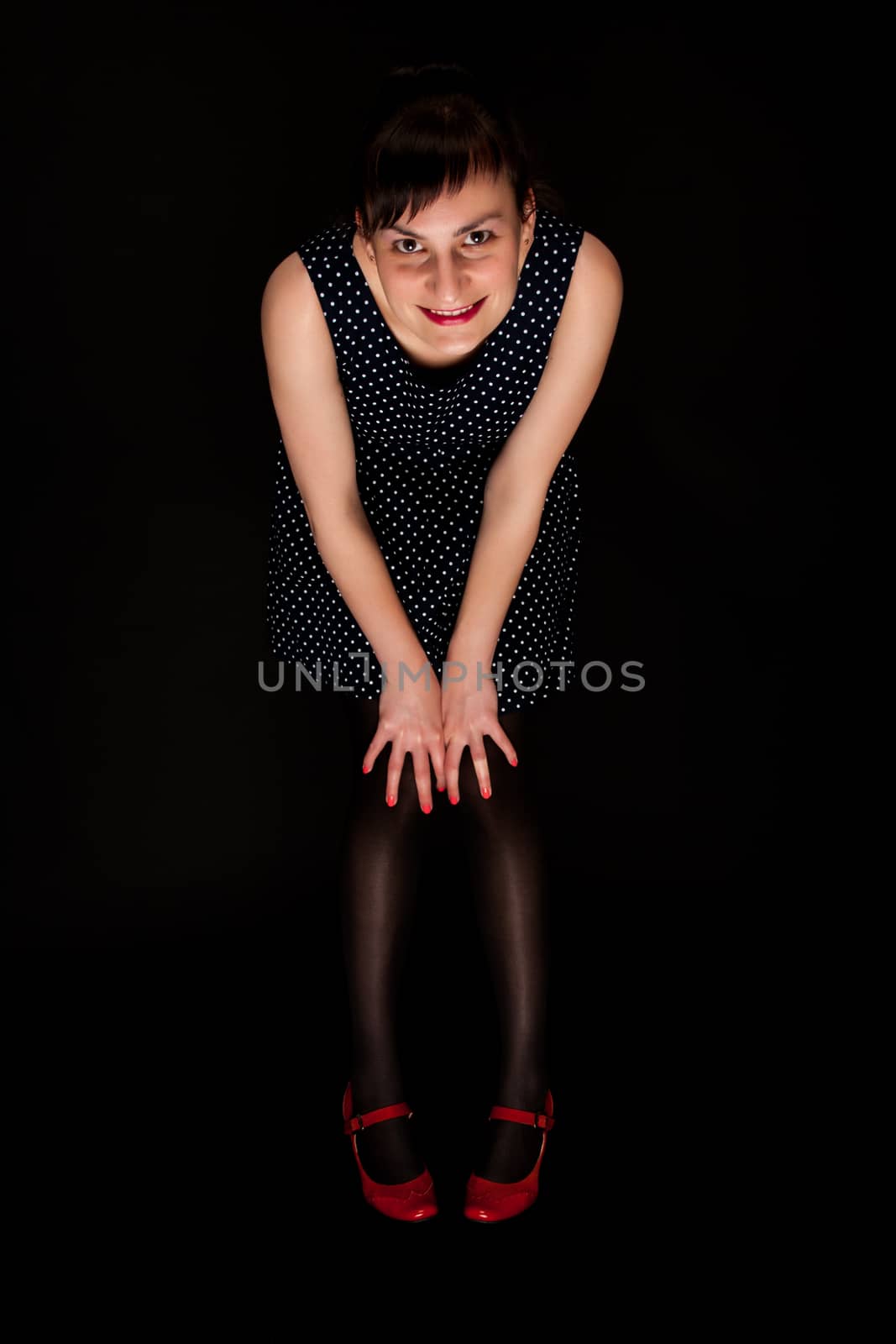 stylish expressive woman with red shoes on black background