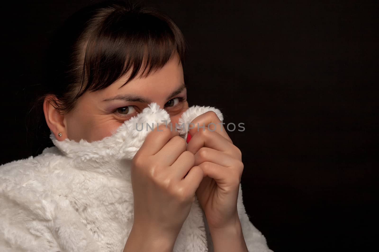 portrait of a stylish expressive woman hiding in white coat in studio