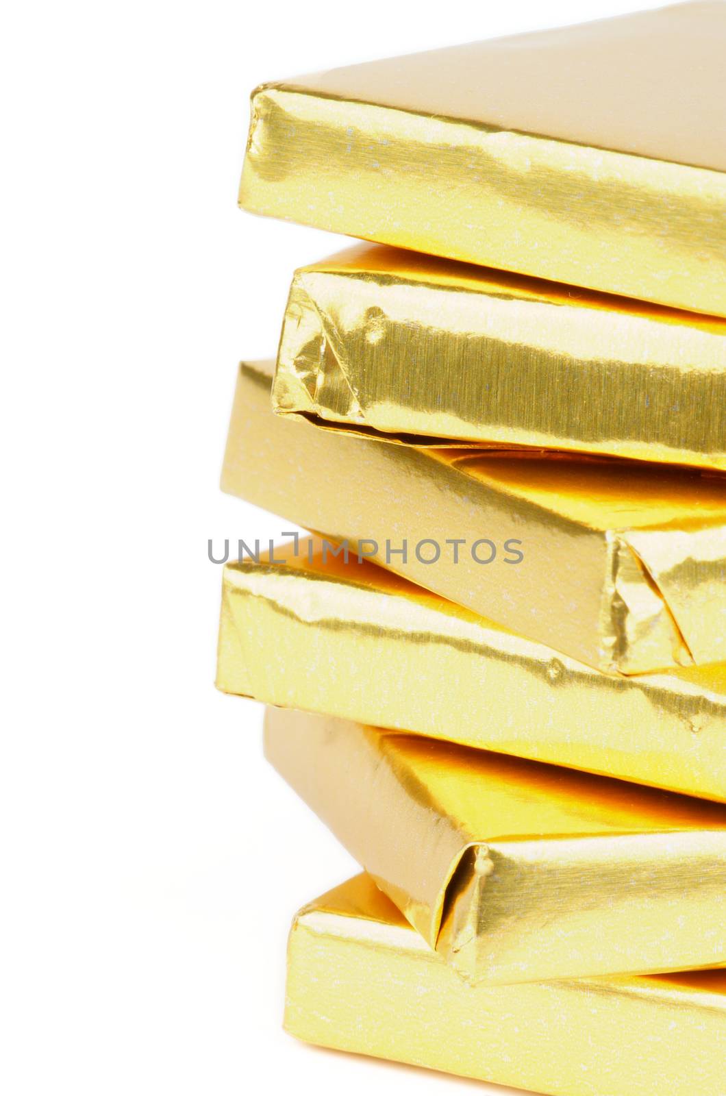 Stack of Chocolate Pieces Wrapped in Gold Paper isolated on white background