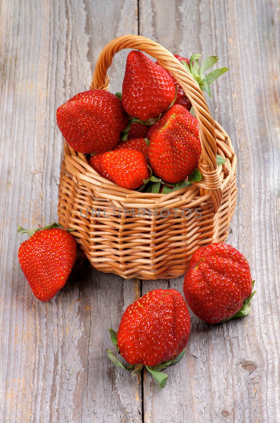 Big Fresh Ripe Strawberries in Wicker Basket isolated on Wooden background
