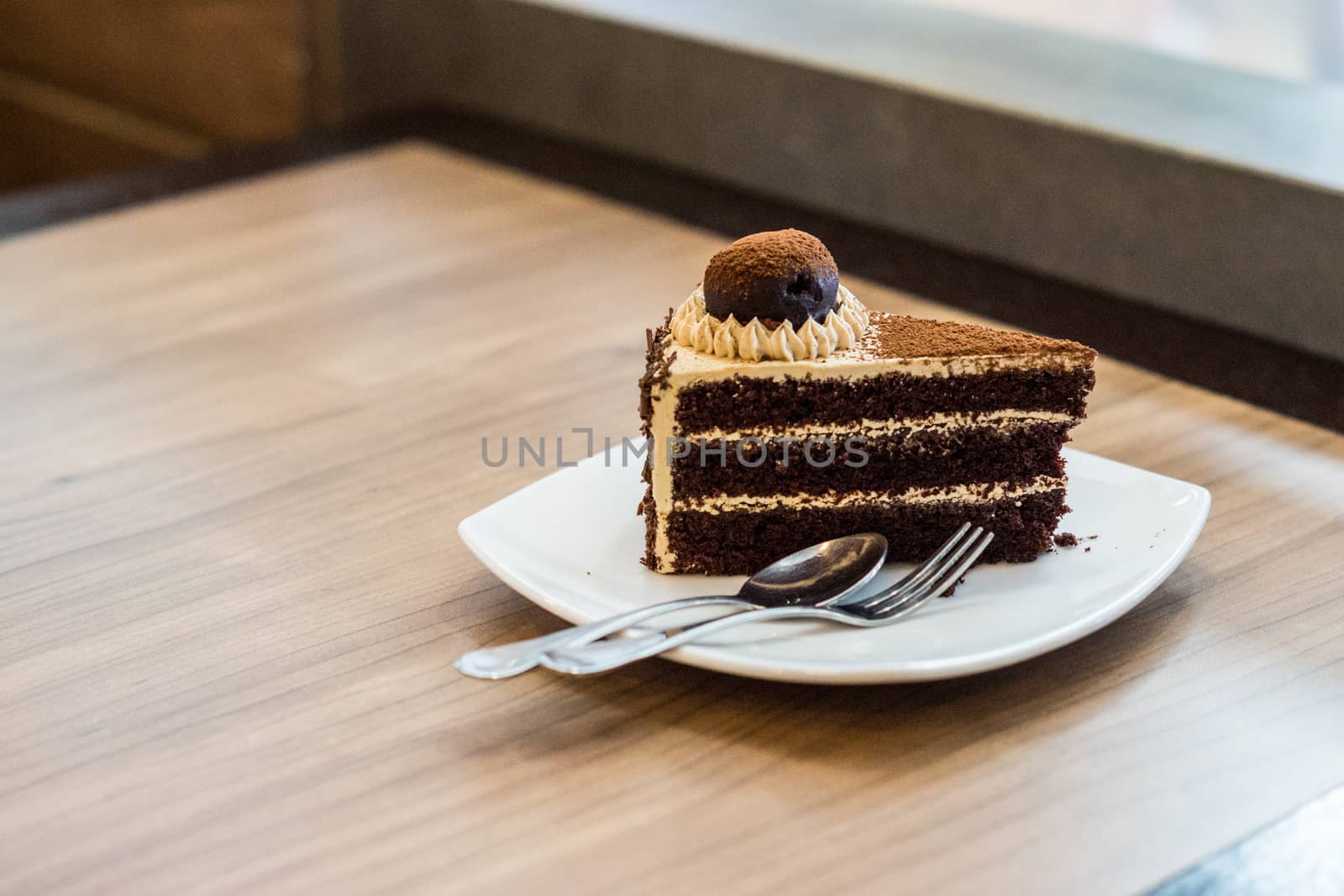 one piece of chocolate cake with chocolate ball toping on wooden table,shallow focus