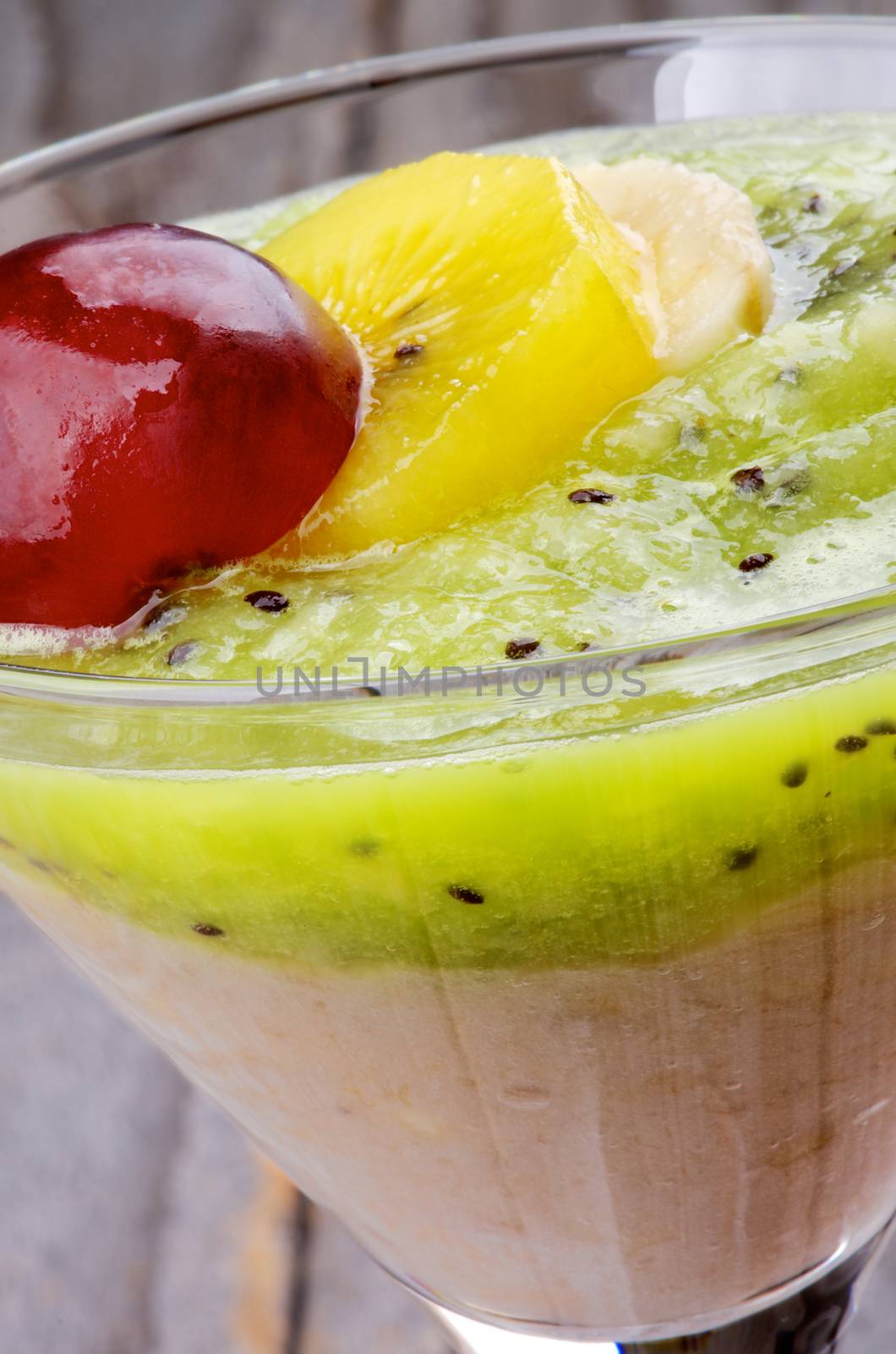 Delicious Fresh Fruits Smoothie with Banana, Golden Kiwi, Green Kiwi and Red Grape closeup in Desert Glass