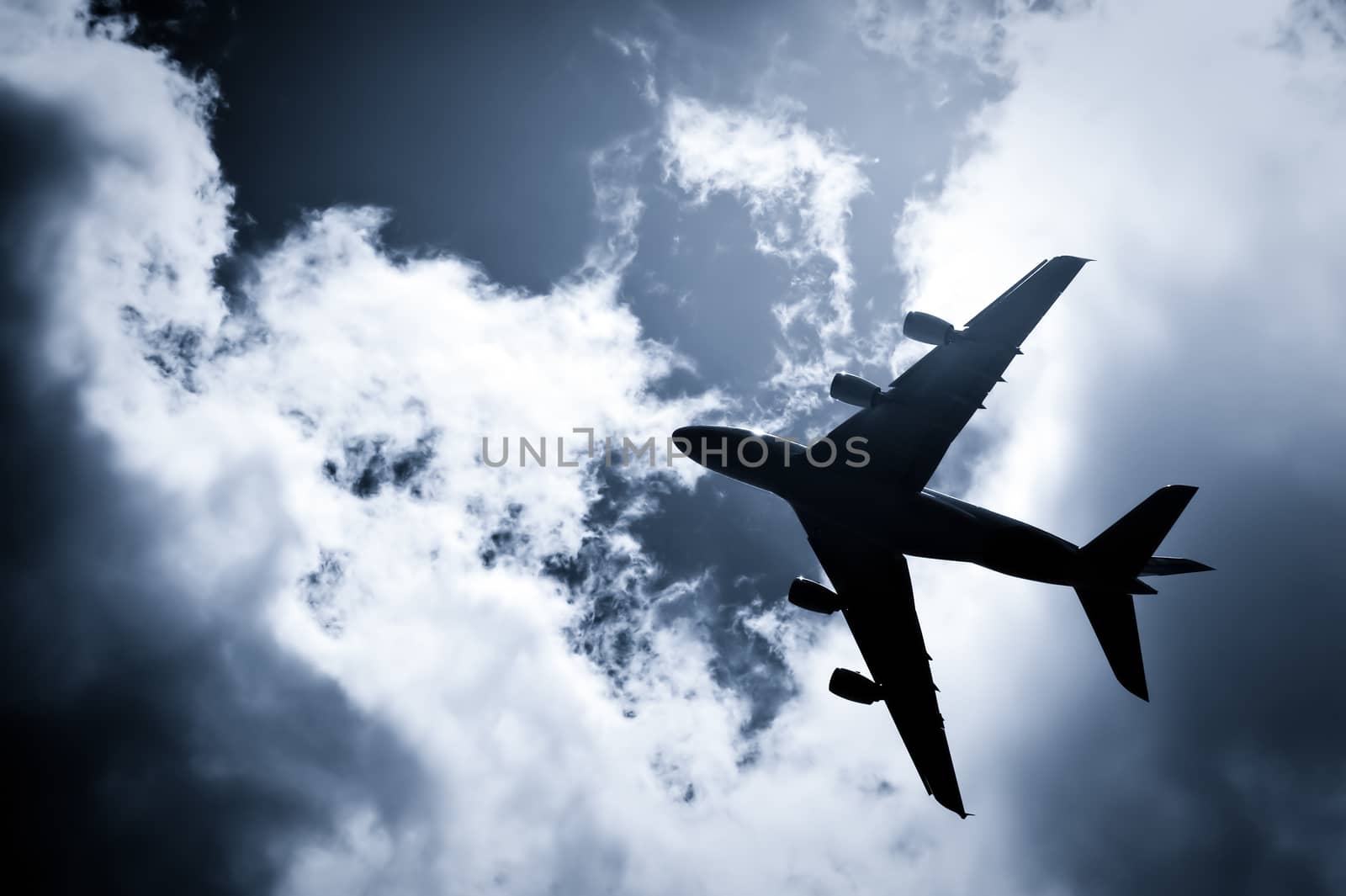 large passenger jet silhouette against a blue tinted sky