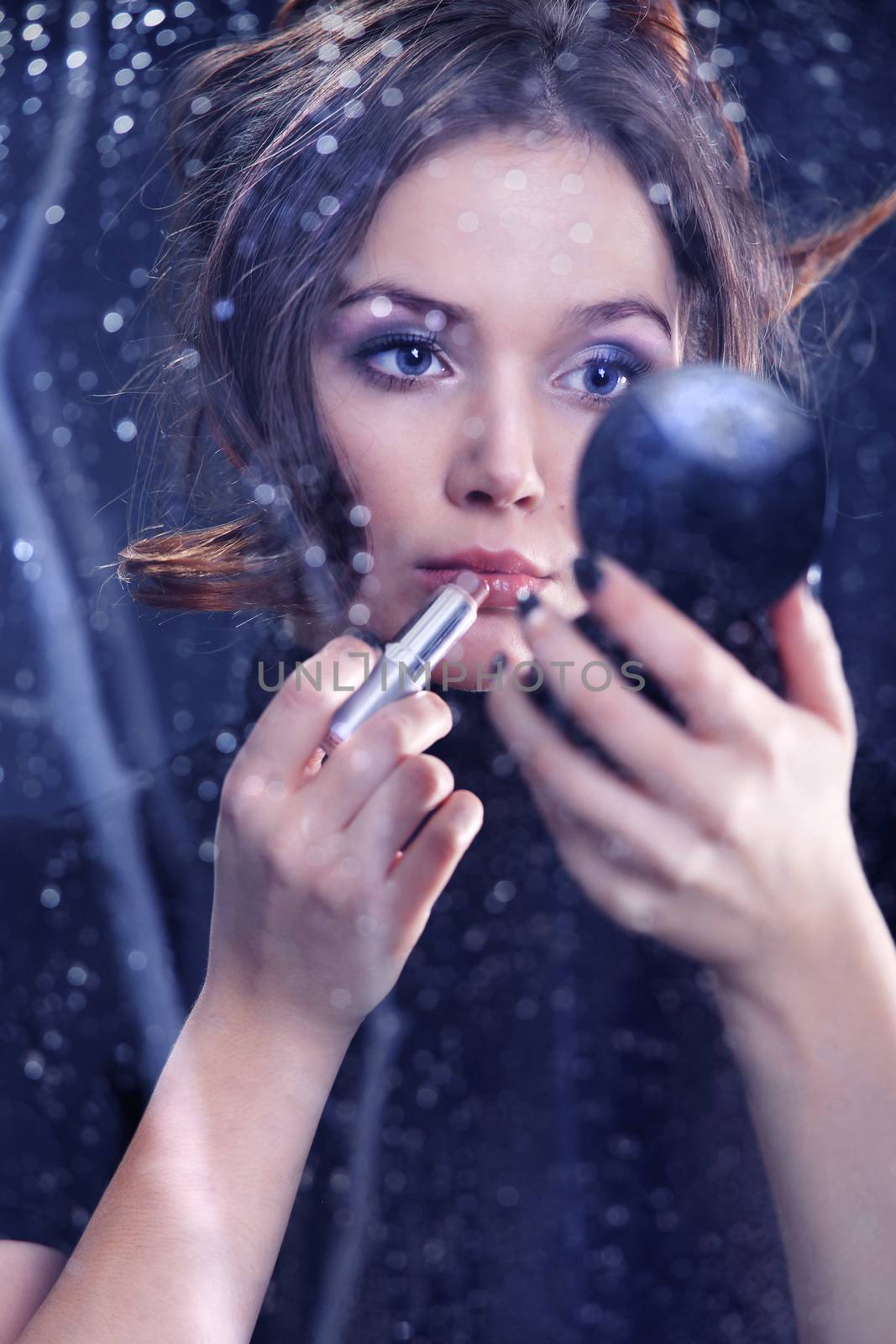 Portrait of a sad woman photographed through the window, a woman paints lips