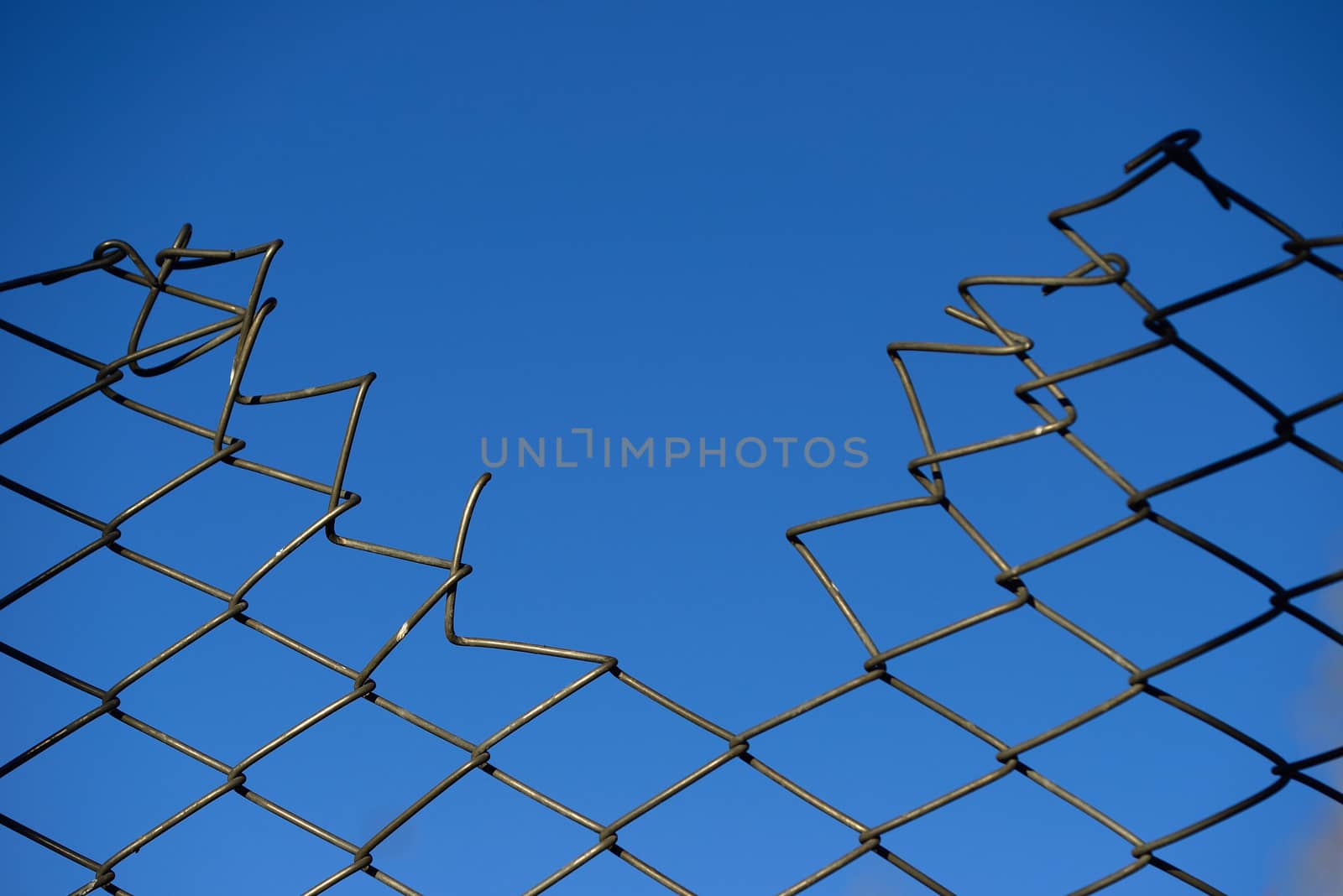 destroyed Steel net fence with blue sky background.