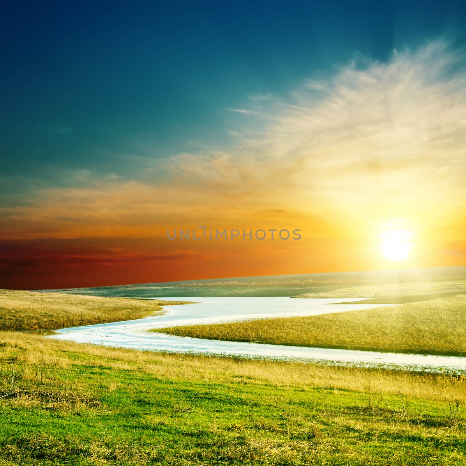 sunset over river in green grass