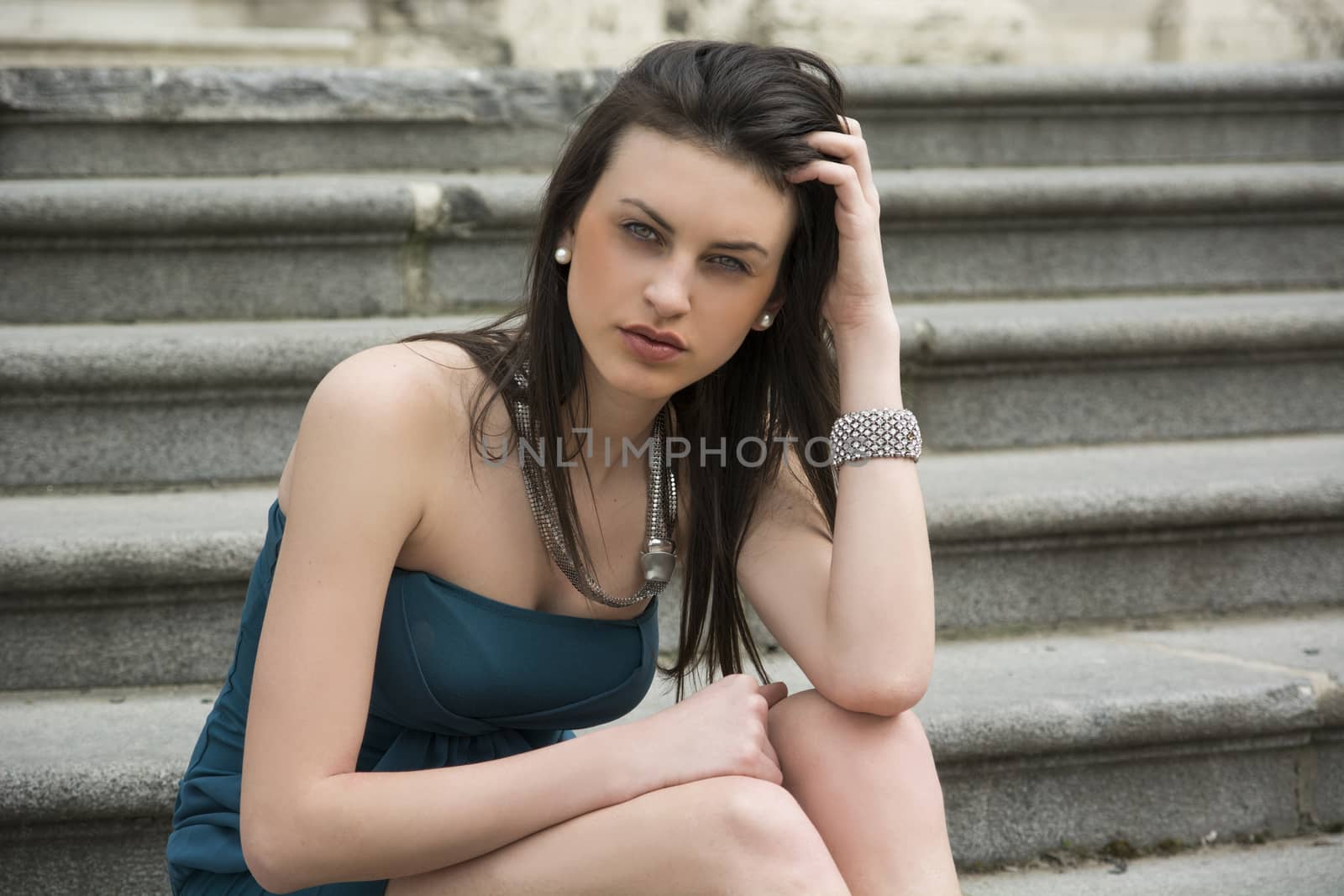 Elegant young woman sitting on stone steps outdoors by artofphoto