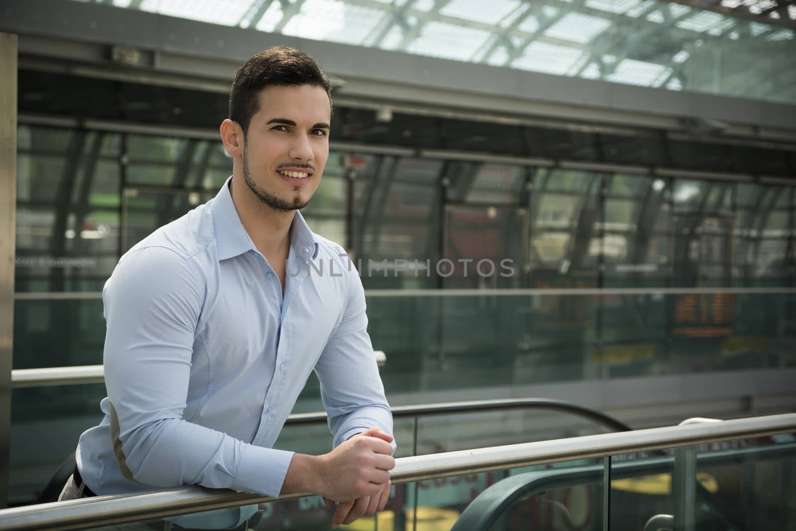 Handsome young man in train station or airport looking at camera and smiling