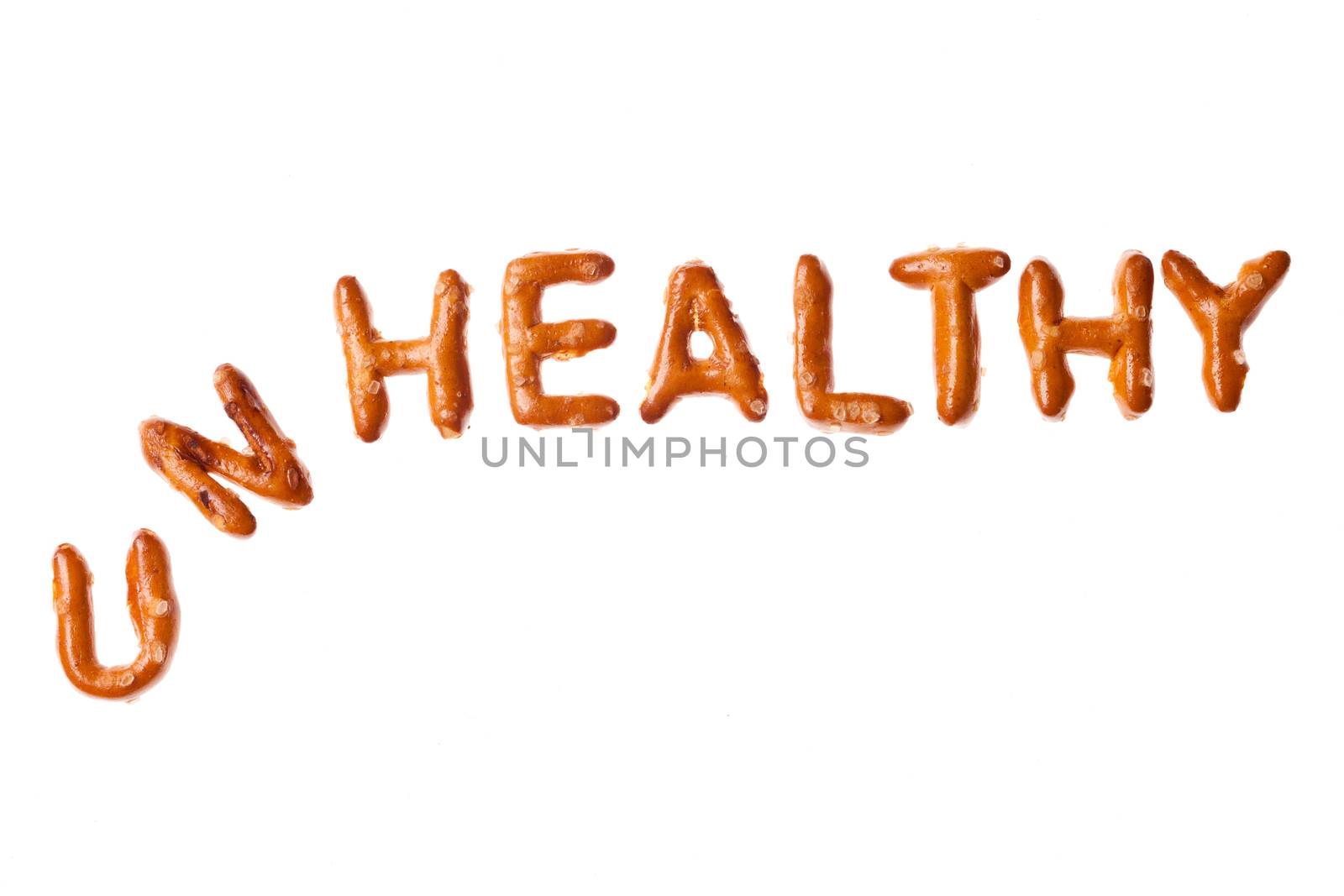 Tumbled word UNHEALTHY written, laid-out, with crispy alphabet pretzels isolated on white background