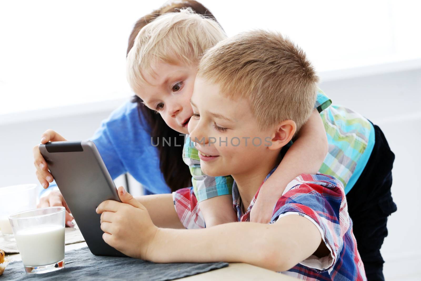 Cute brothers with tablet during breakfast
