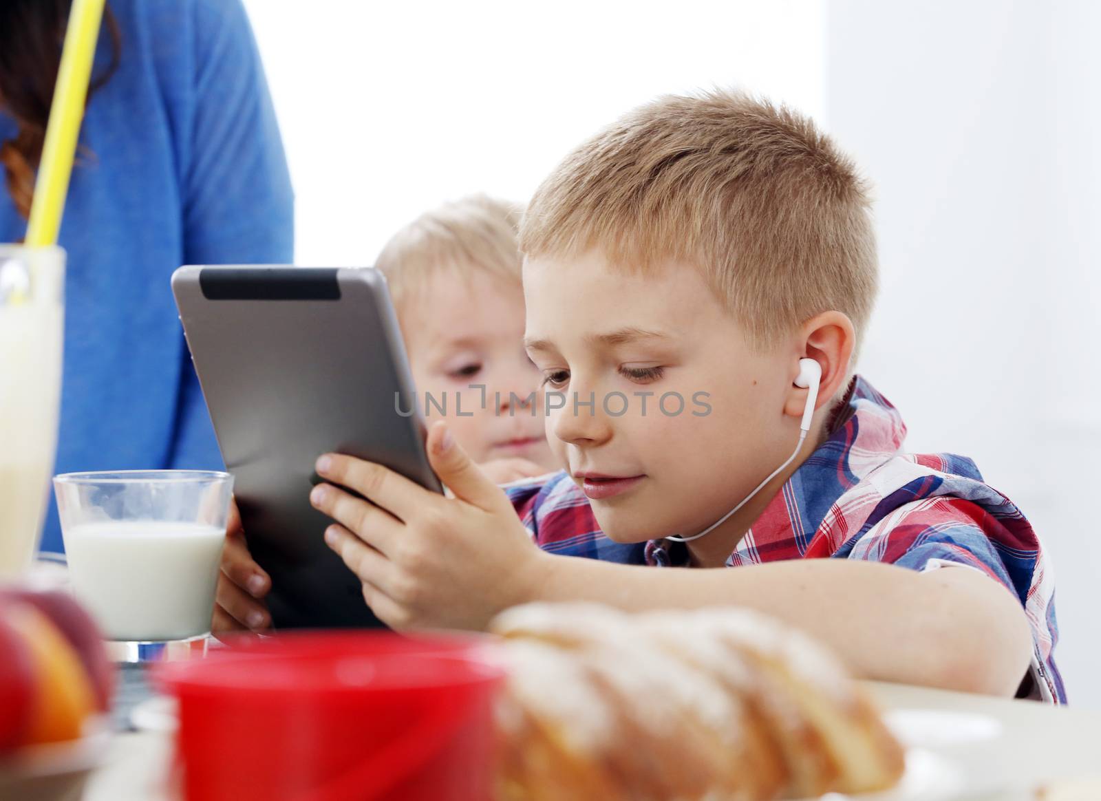 Cute brothers with tablet during breakfast