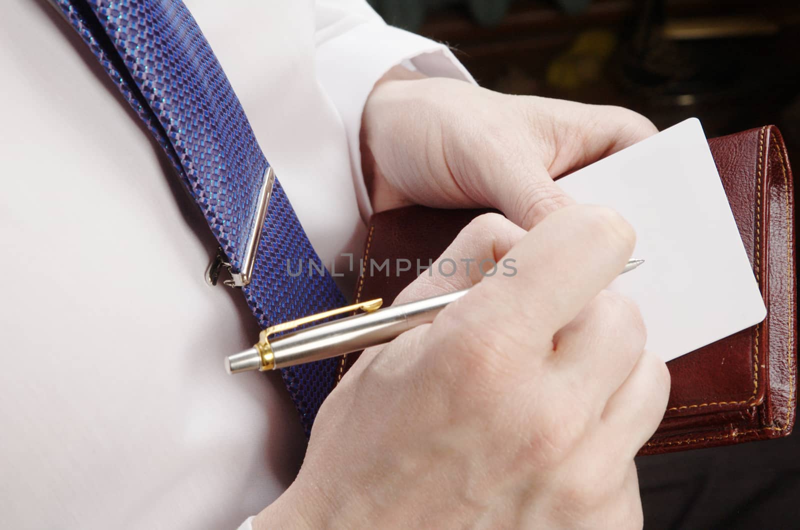 Businessman in white shirt holding visit card and pen