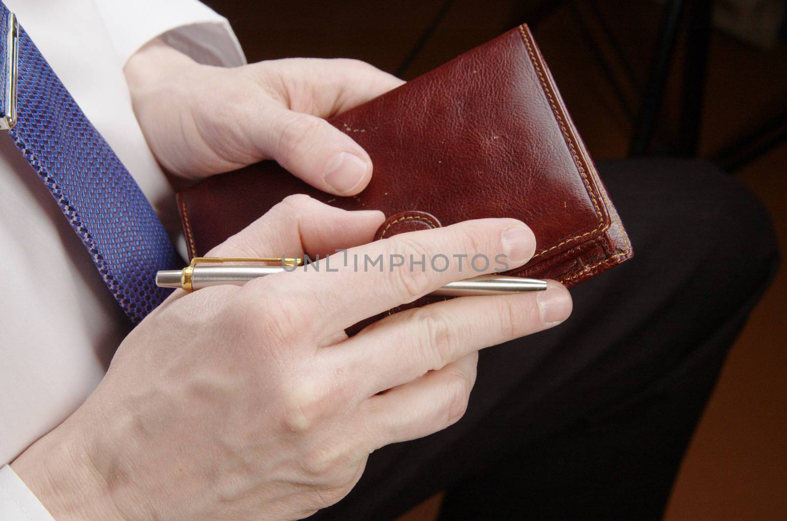 Businessman in white shirt holding leather wallet and pen