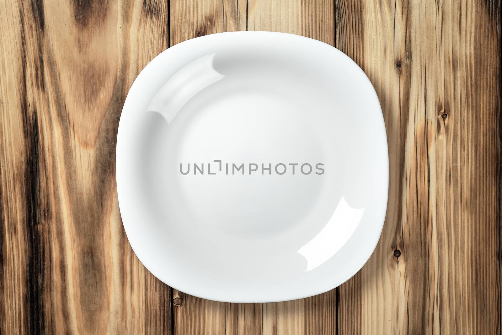 Empty white plate on wooden table background. Top view