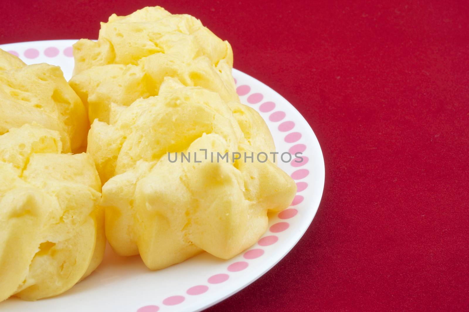 Eclair yellow placed on a white plate on a red background.