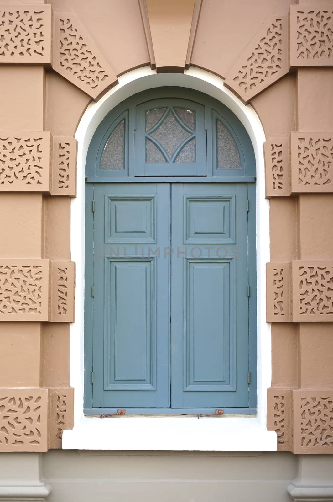 Blue window in brown wall of the building, which is located at Grand Palace