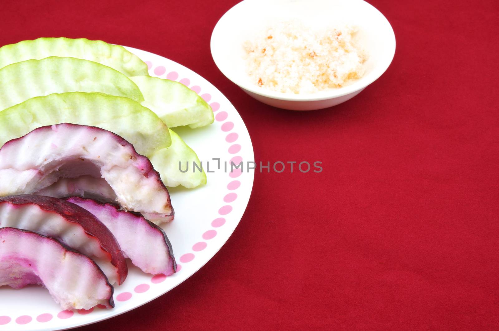 Malay apple and guava slices with salt and pepper in a plate with red background.