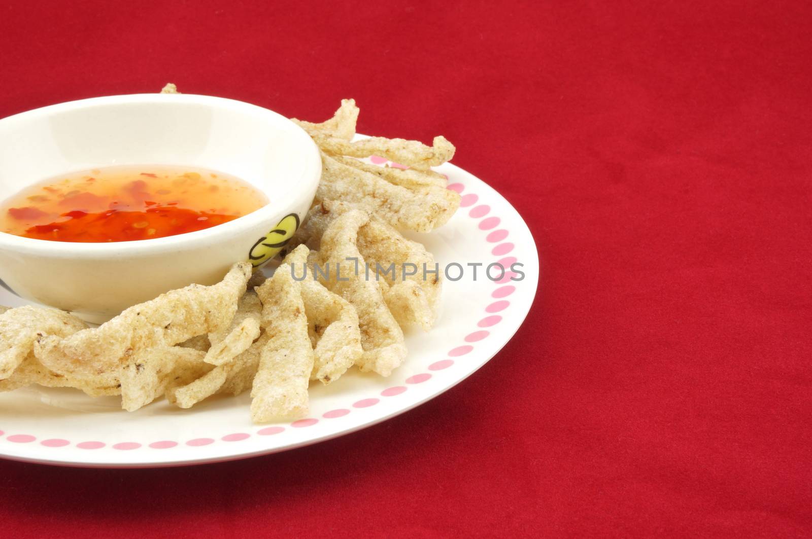 Shiitake mushroom snack in plate with chilli sauce placed on a red background.