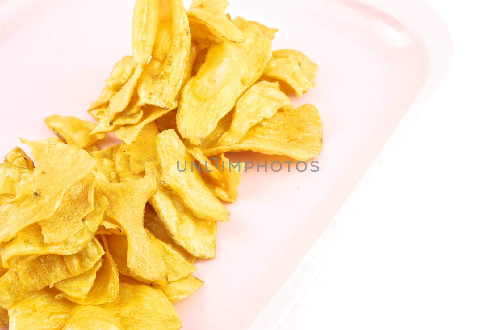 Sliced yellow cassava fried and coating sugar paste on pink tray with white background.