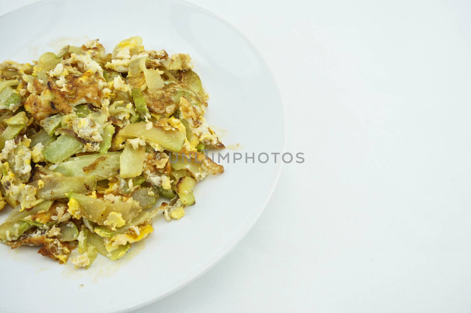 Chayote sliced fried with egg on white dish with white background.