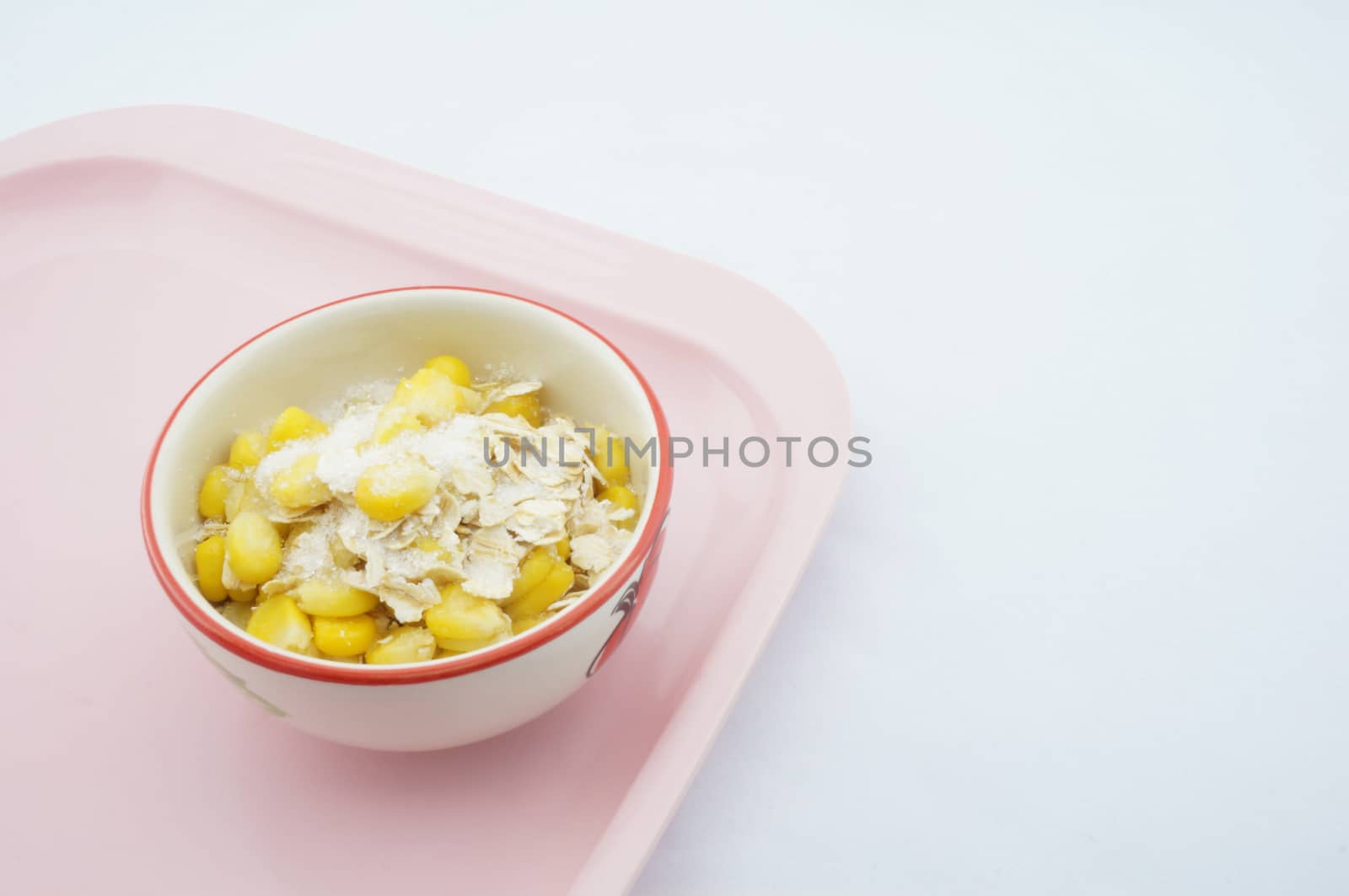 Mix corn, oats and sugar placed on pink tray with white background.