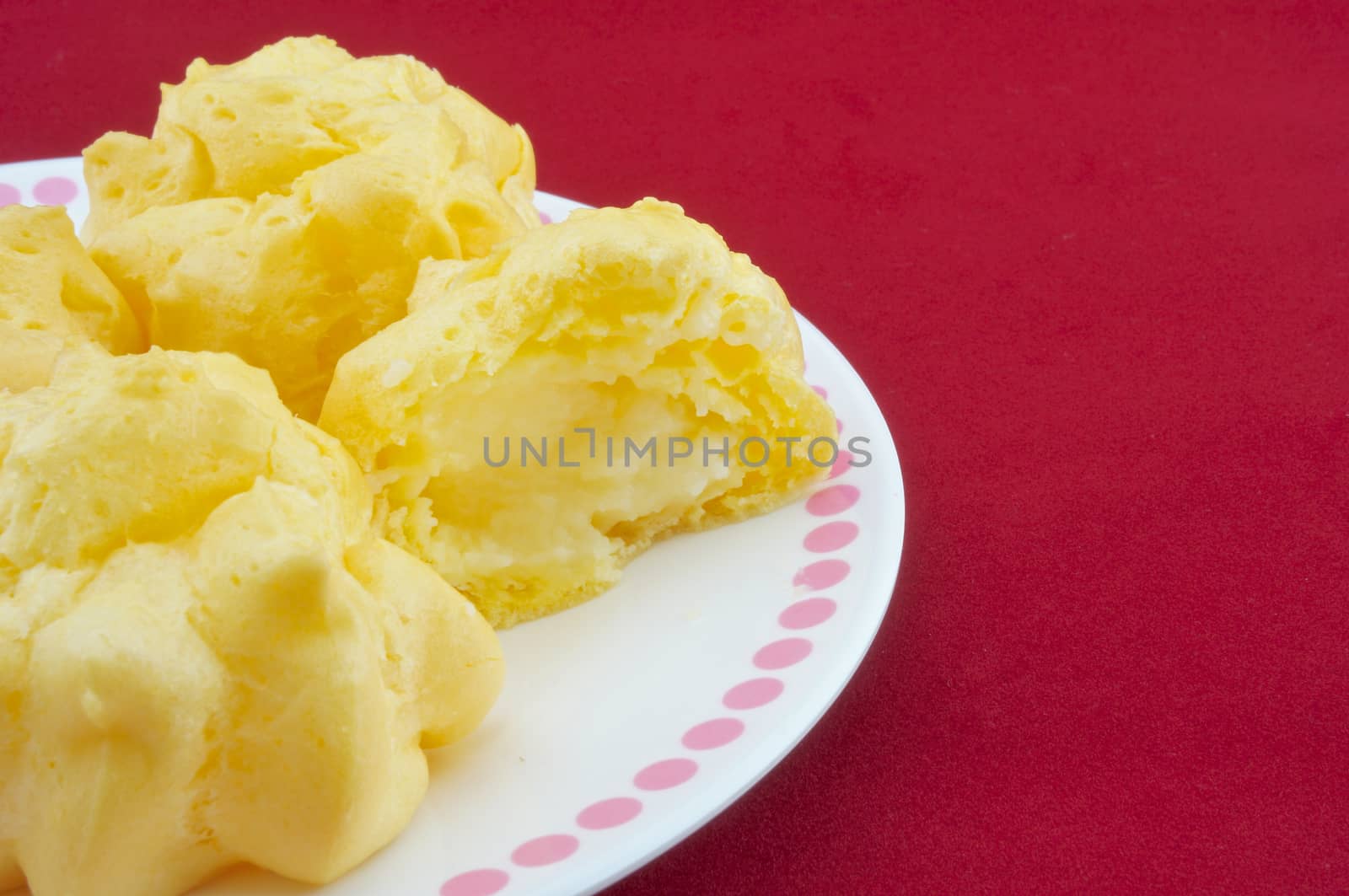 Eating eclair yellow placed on a white plate on a red background.