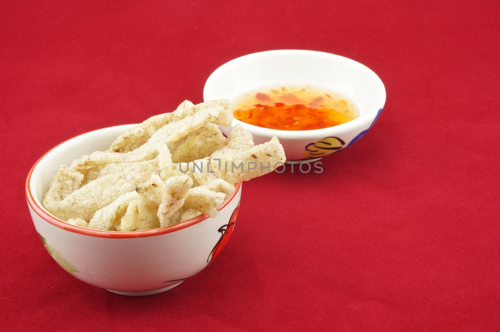 Shiitake mushroom snack in cup with chilli sauce placed on a red background.