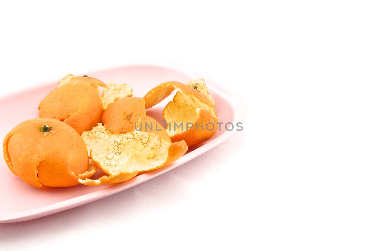 Orange peel placed on the pink tray with white background.