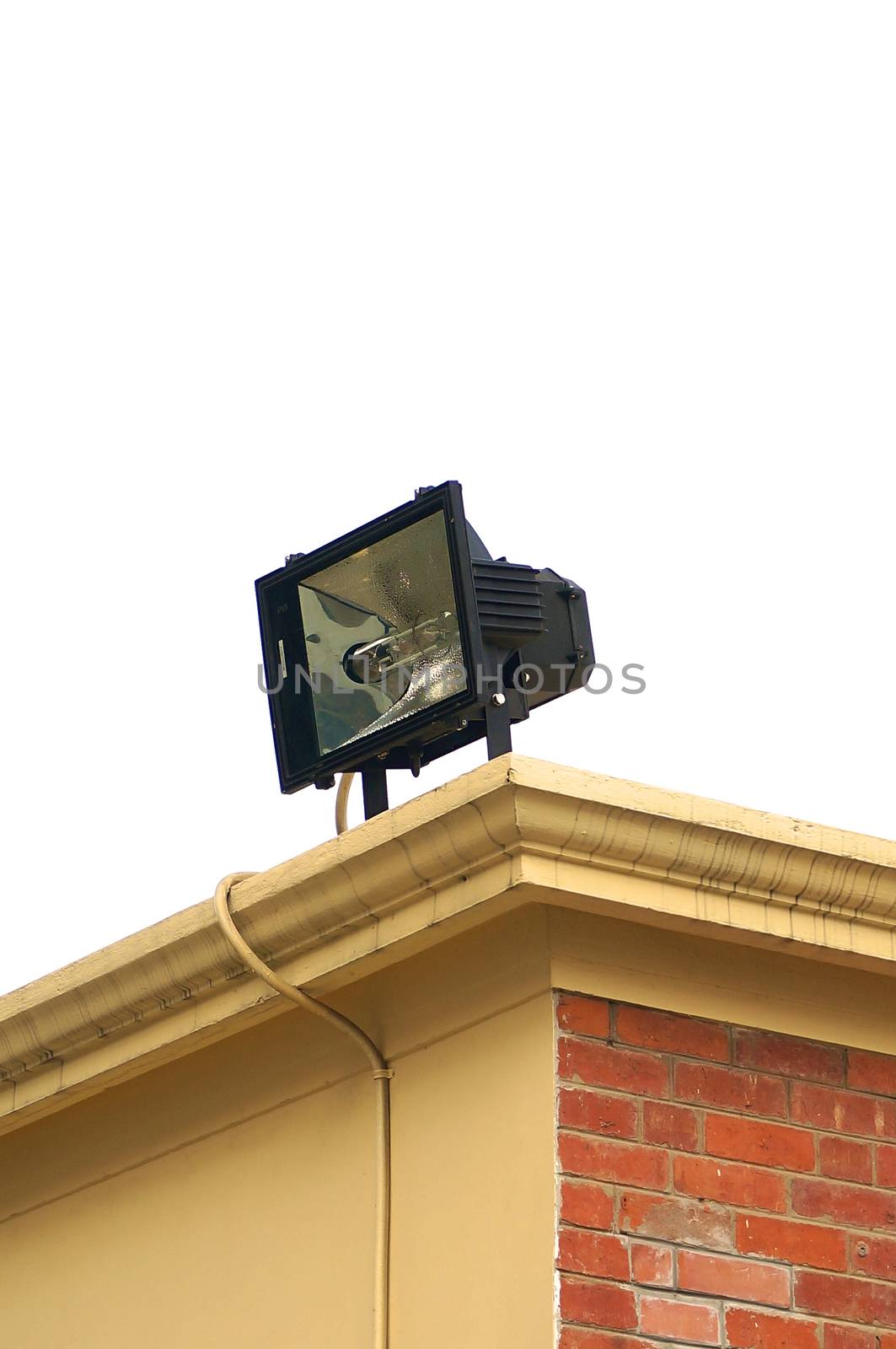 Spotlight mounted on the orange brick building plastered with cement and painted yellow.