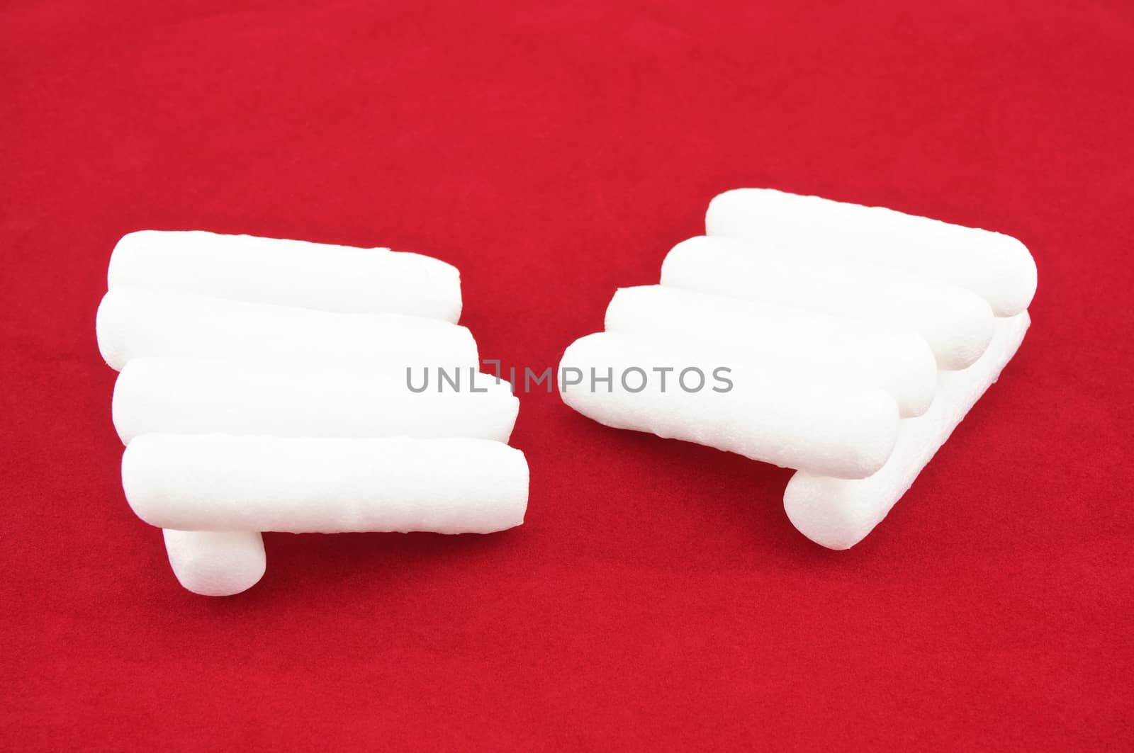 Foam shape as cylinder  placed like hand on red background.