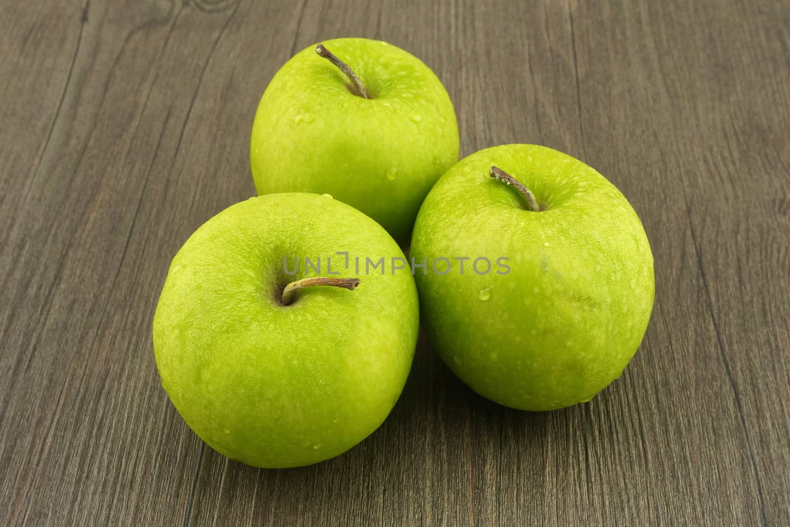 Three fresh green apples put on dark brown wood background.