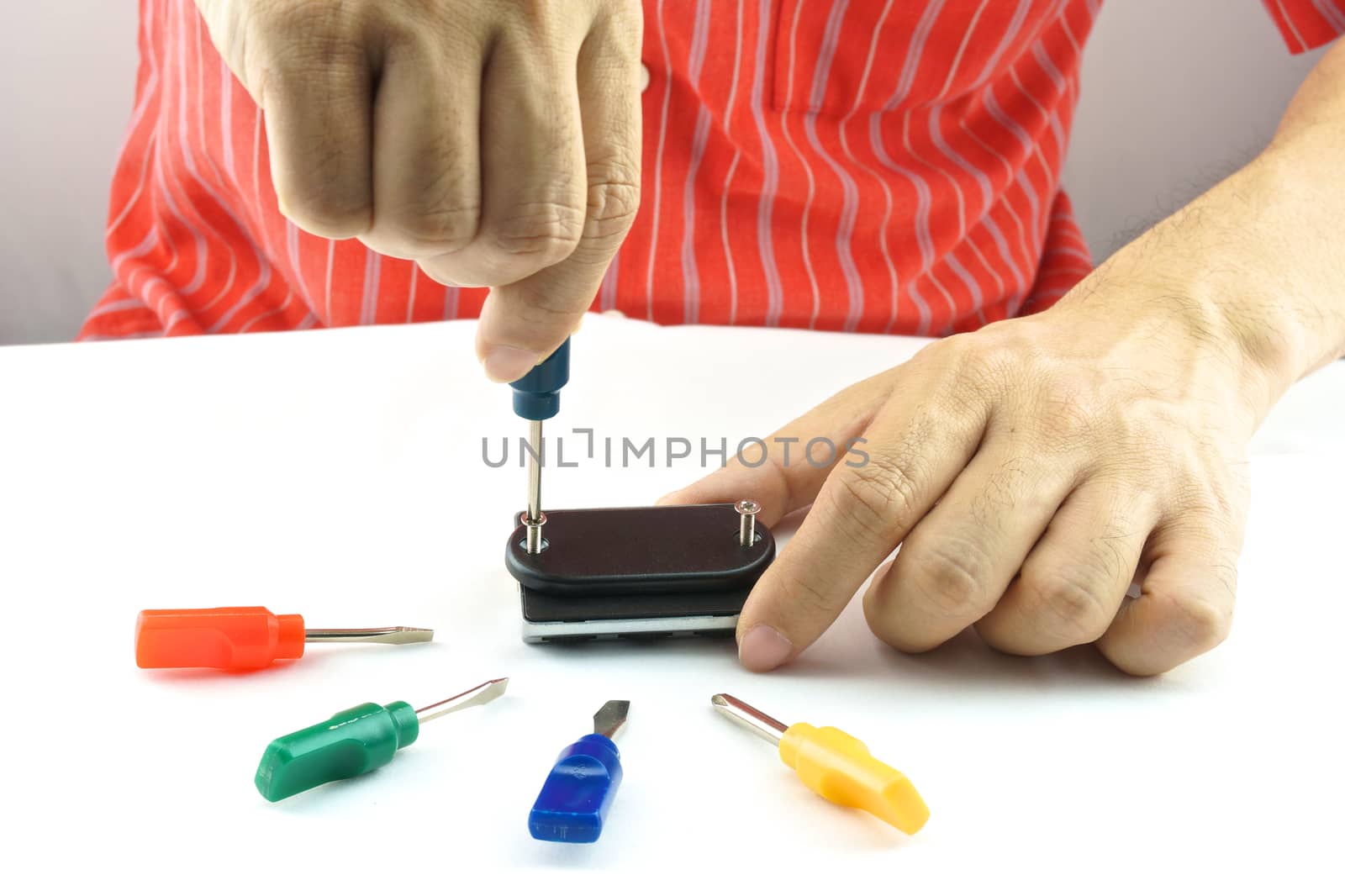 Man using screwdriver with screw for minor repair with white background.