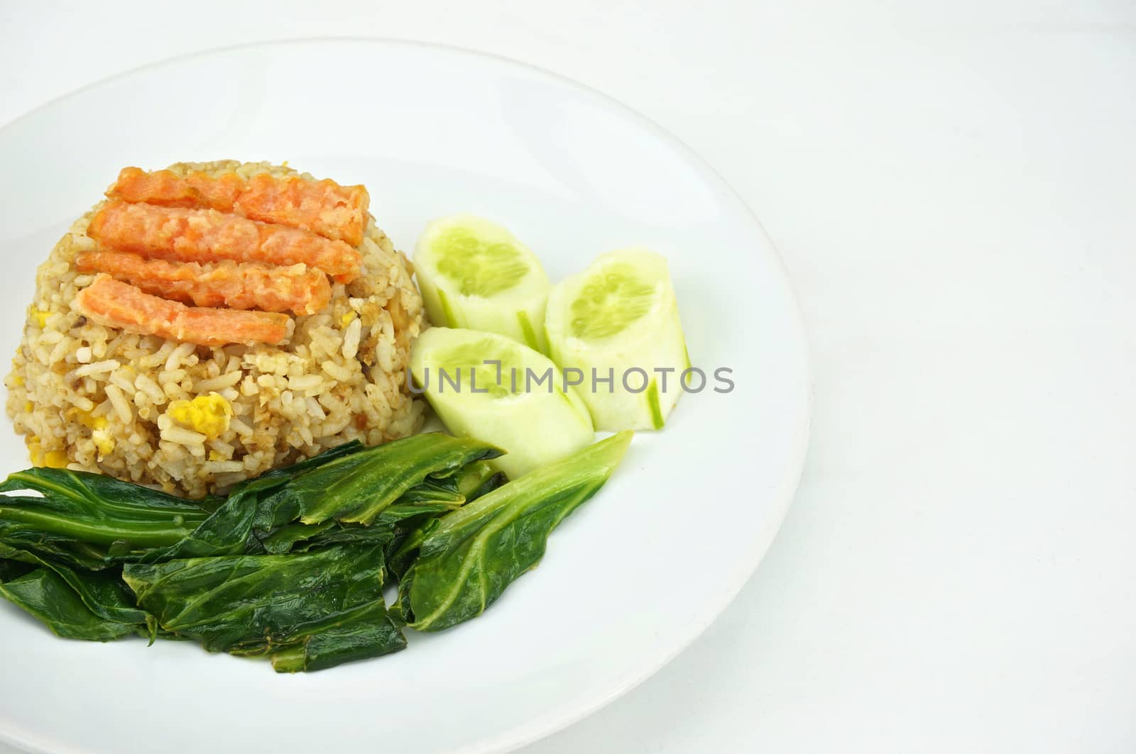 Shrimp fried rice vegetarian with kale, carrots and cucumber on a plate with white background.