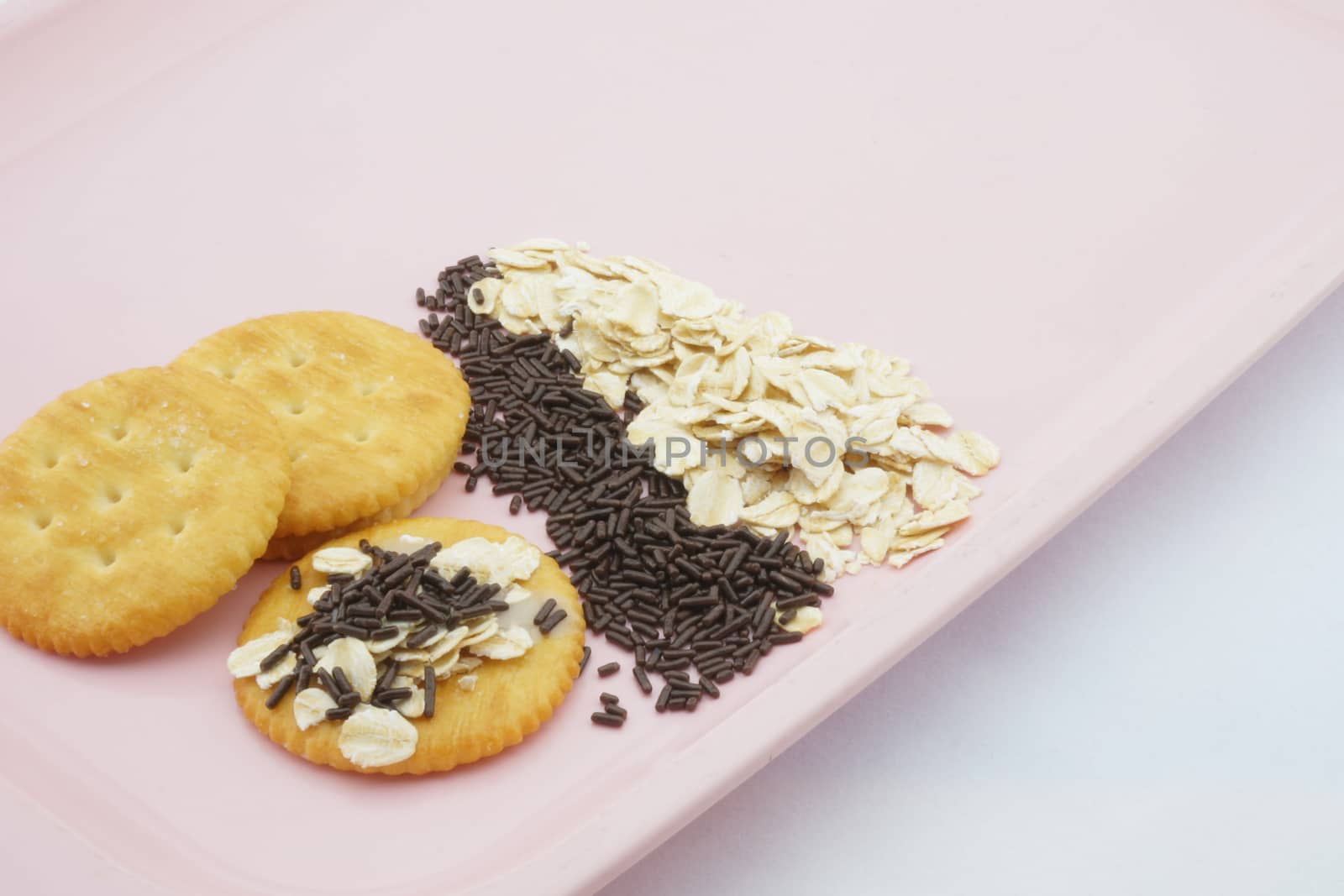 Crackers with oat, chocolate and sweetened condensed milk placed on pink plate.