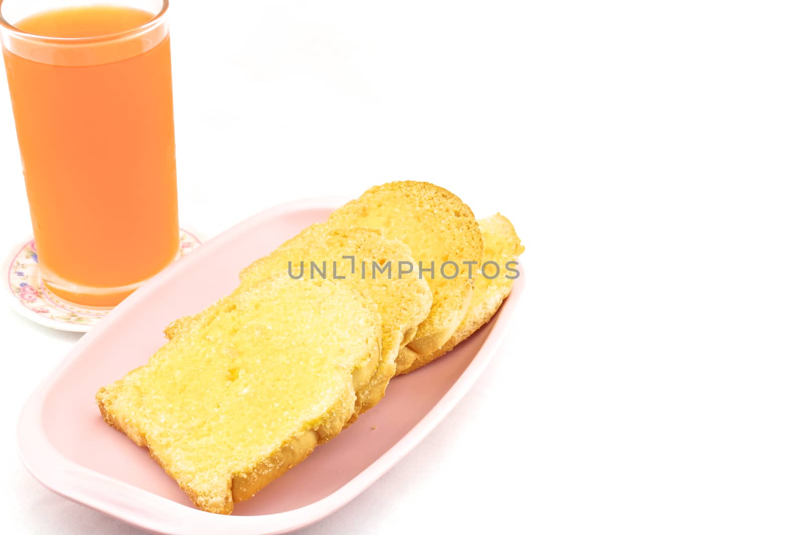 Bread baked with butter and sugar placed in a pink tray with orange juice on white background.