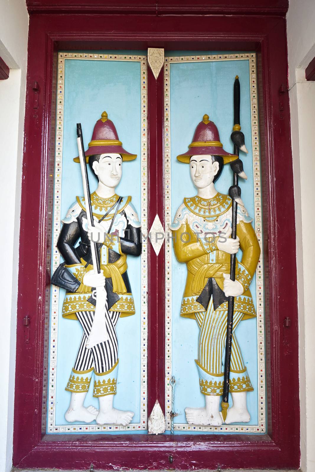 Soldier hold gun and spear on door of the building, which is located on the Temple of the Emerald Buddha.