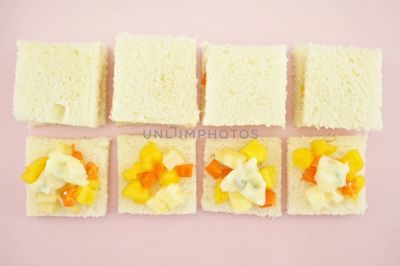 Carrot, Mango, apple and cucumber sliced put on small bread with cream salad in row for make sandwich on pink tray.