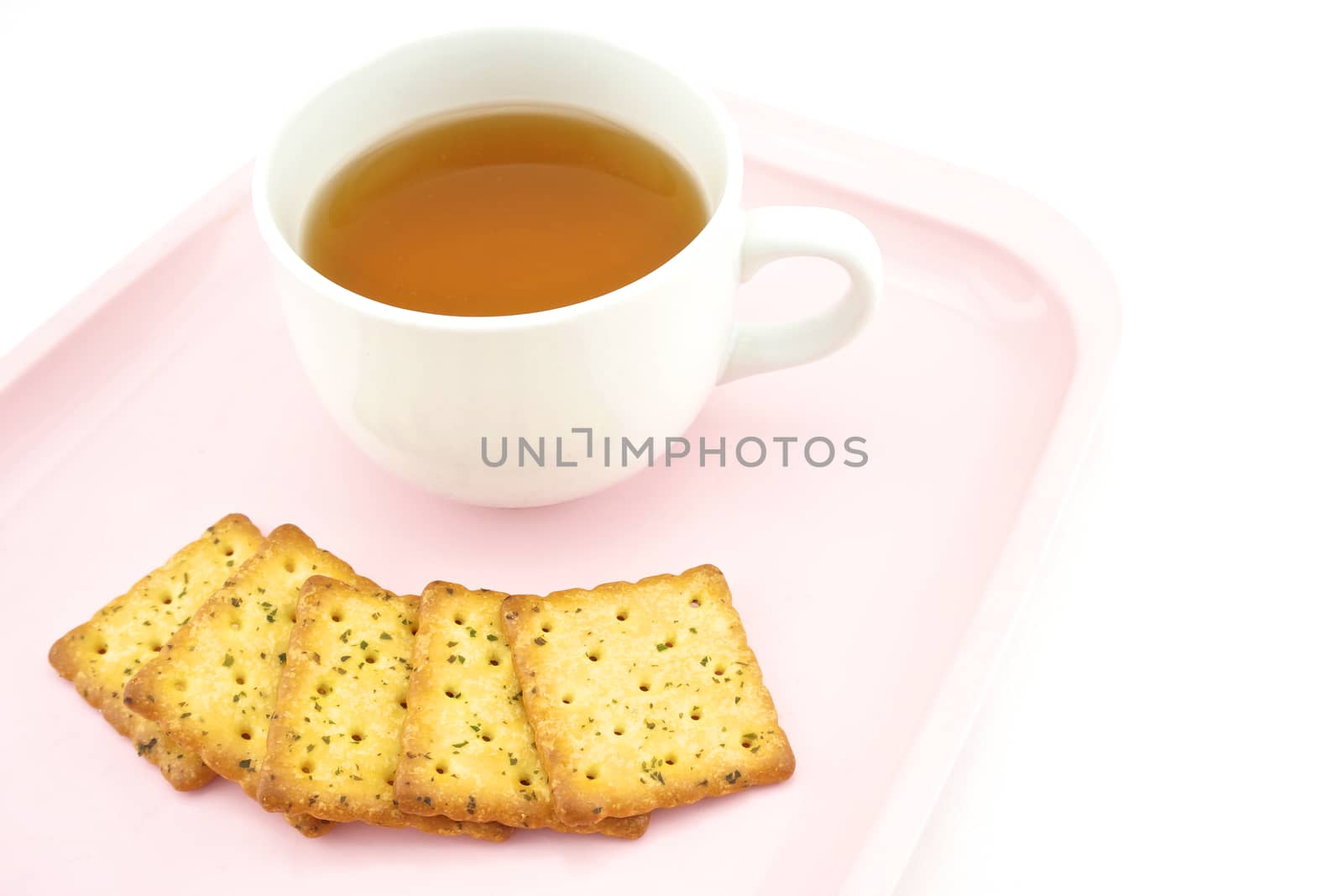 Tea in white cup and biscuits at side put on pink tray with white background.