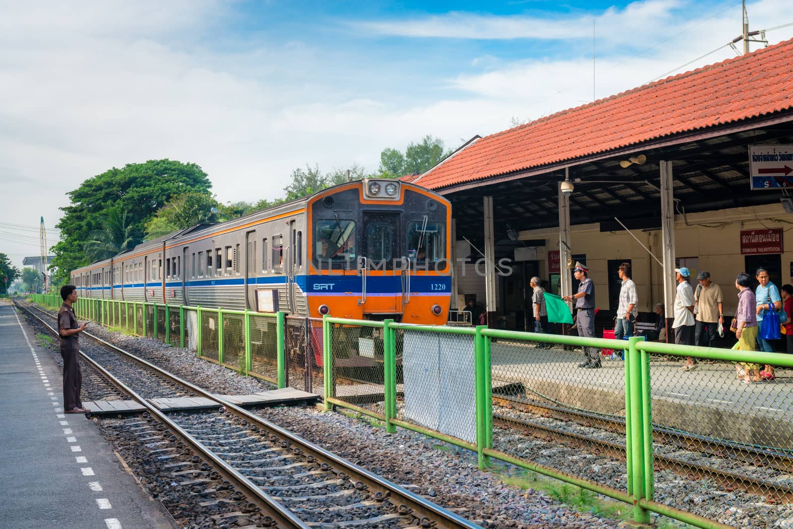 DONG MUEANG, THAILAND - 21 NOV 2013: Locomotive with train arrives at railway station with people on outdoor platforms