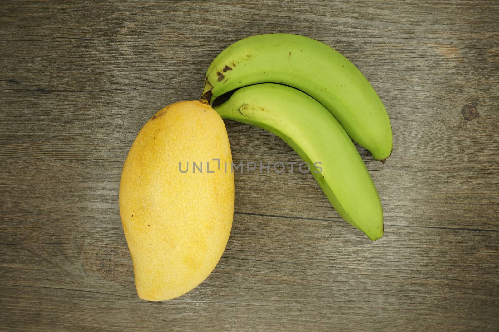 Mango or Mangifera indica and banana on wood background by eaglesky