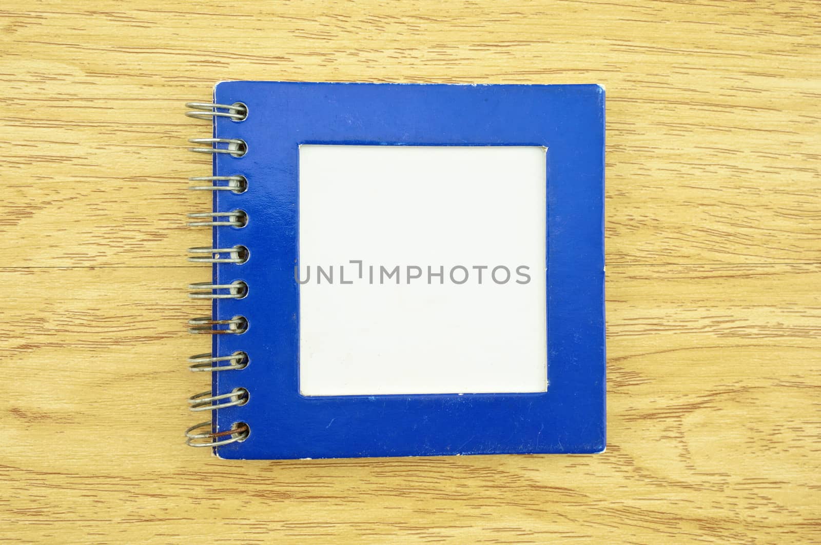 Old blue notebook with rusty wire and dirt on paper place on wood background.