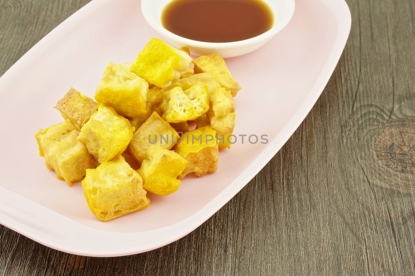 Tofo fried with soy in pink tray on wood background.