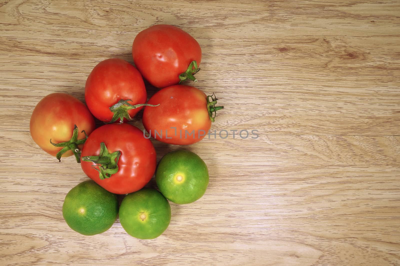 Red tomato and green lemon is colorful vegetable put on wood background.