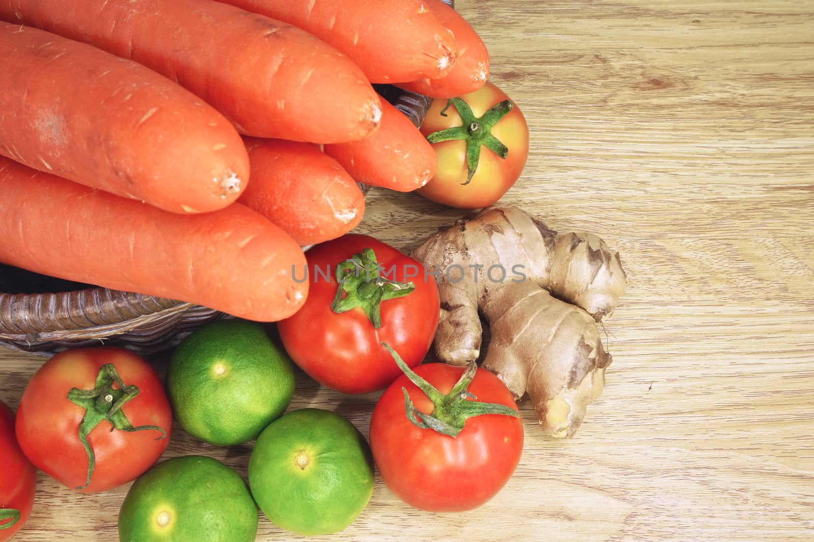 Tomato, lemon, ginger and carrot in basket is colorful vegetable put on wood background.