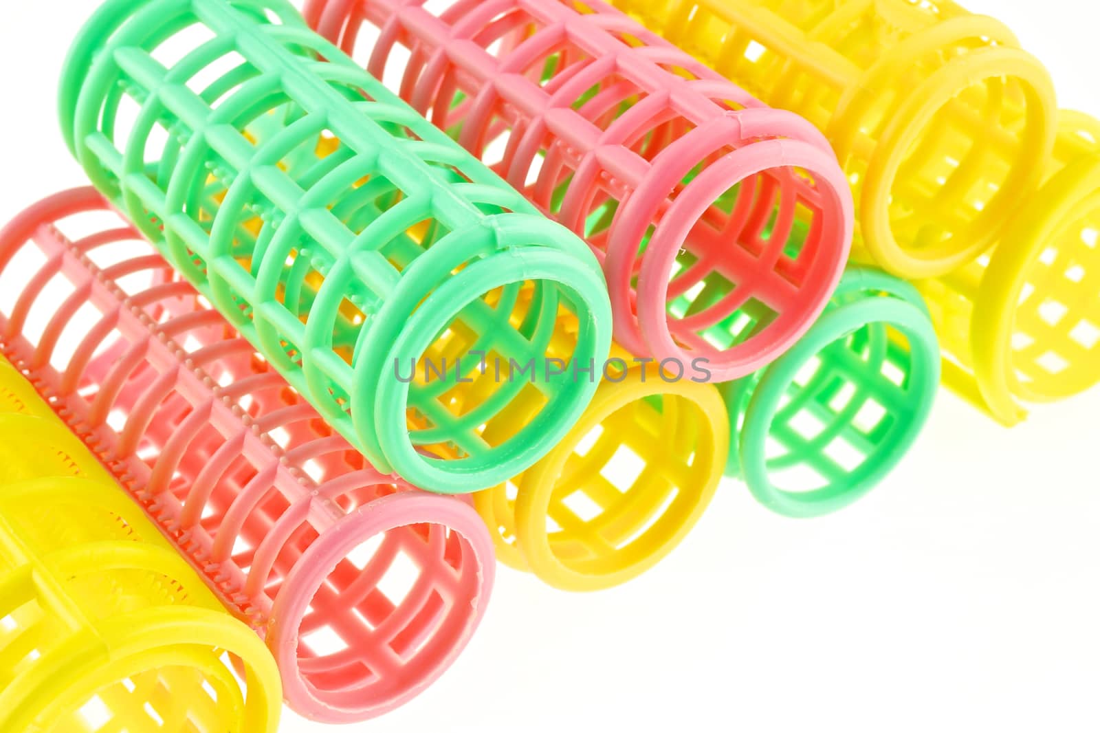 Green, pink and yellow curler stacked isolated with white background.