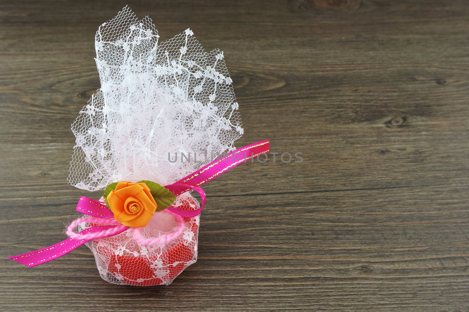 Camphor aroma in red cup wrapped in white mesh place on left with wood background.