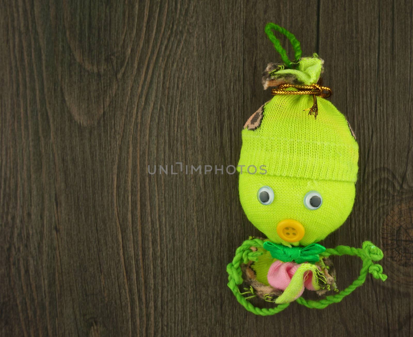 Green doll made from yarn with camphor aroma as octopus with wood background.