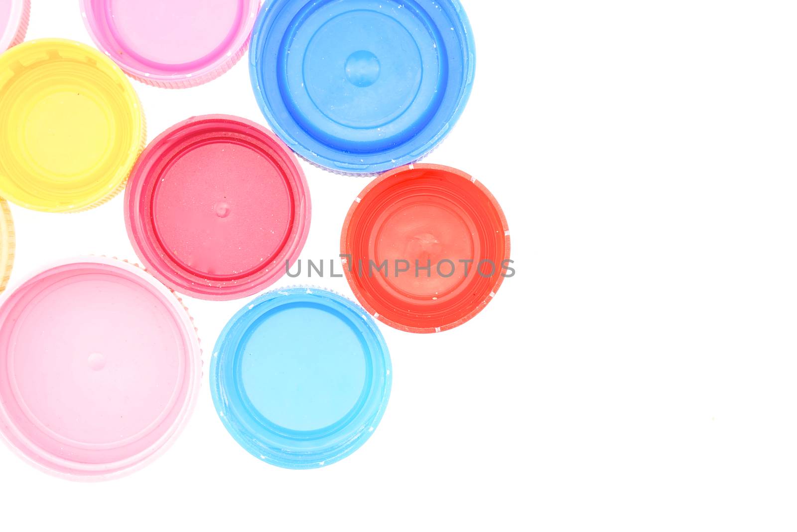 Red, blue, pink and yellow plastic bottle cap for recycling garbage isolated with white background.