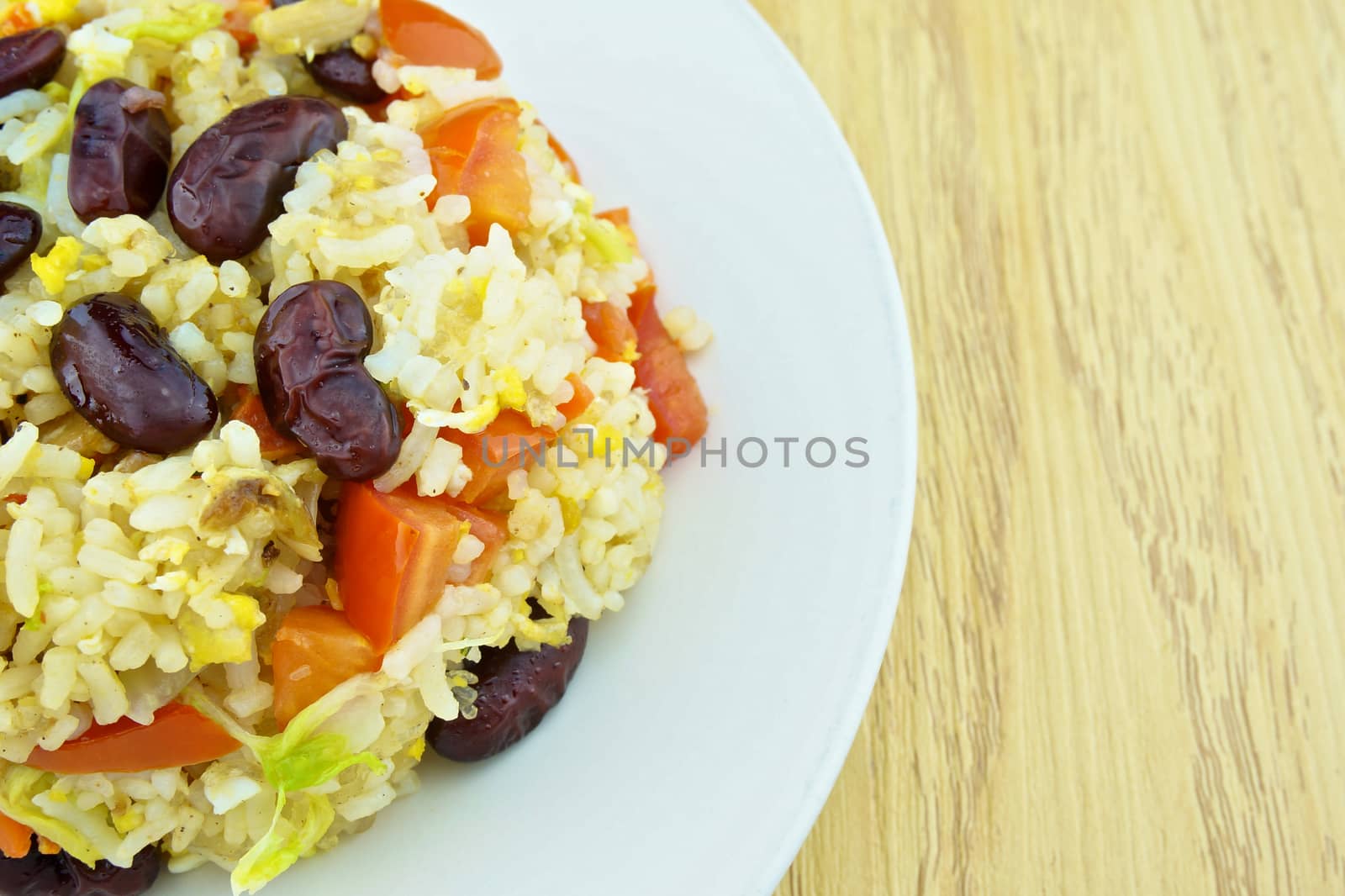 Close up fried rice with red bean, tomato and lettuce is vegetarian food on wood background.