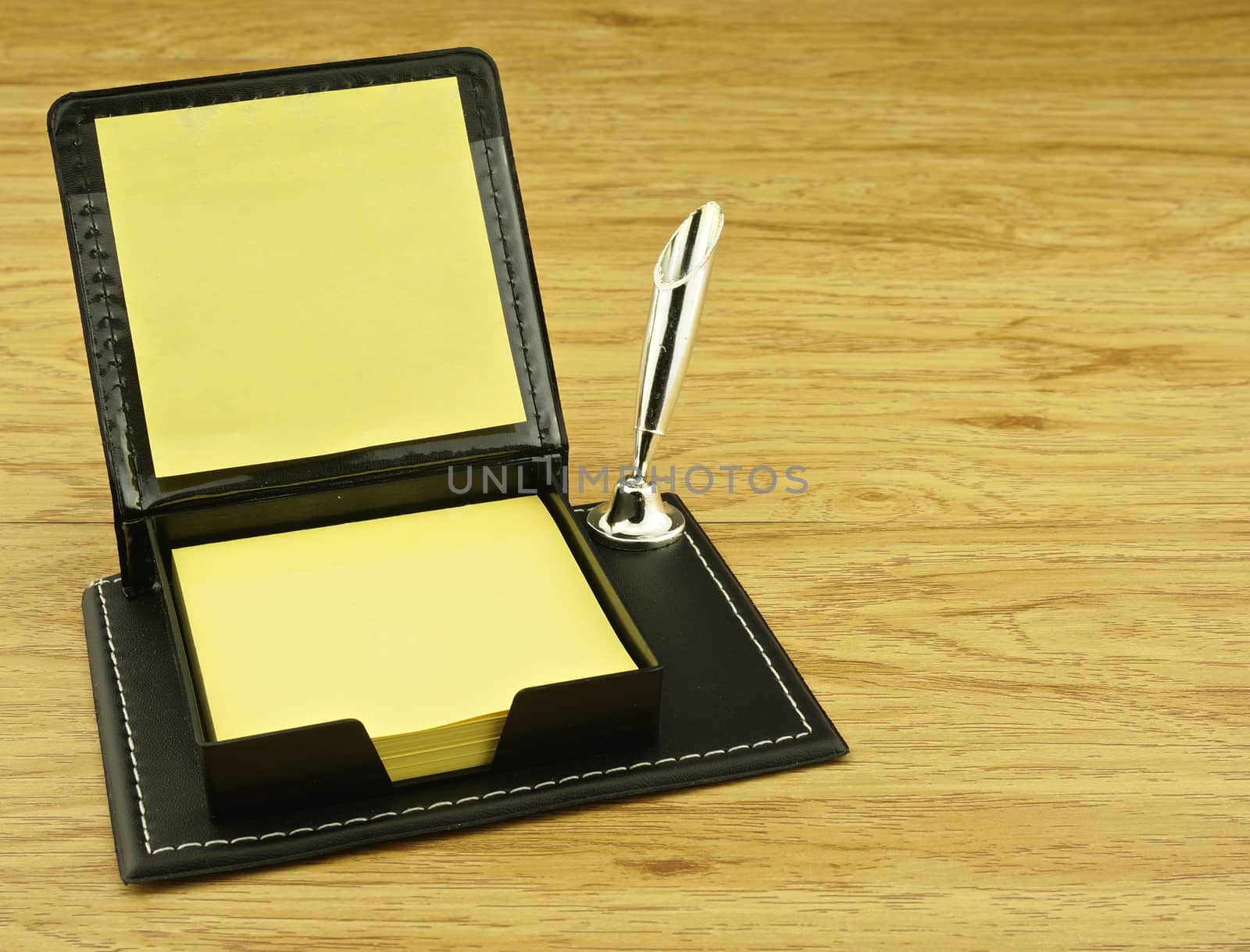 Black box and yellow paper note place on left with wood background.